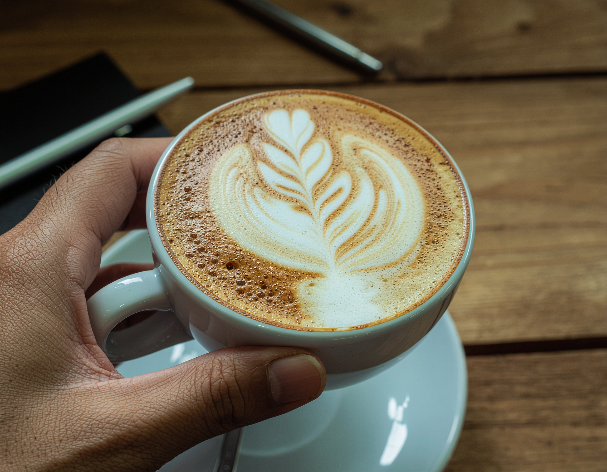 Woman entering numbers on a laptop with calculator, budget sheets, and a coffee mug on the desk